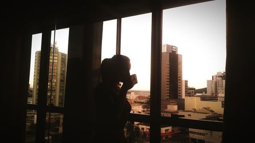 Side view of man standing by window in city