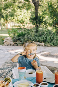 Girl eating food while sitting outdoors