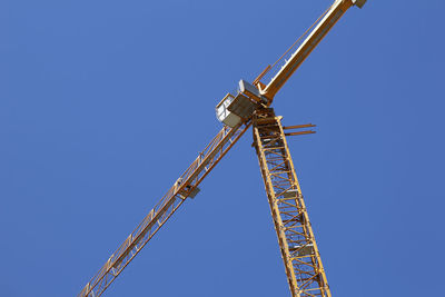 Low angle view of crane against clear blue sky