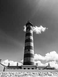 Low angle view of lighthouse by building against sky