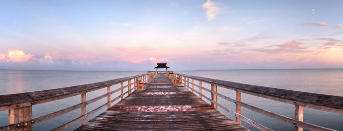 Pier over sea against sky during sunset