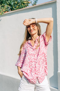 Portrait of young woman standing against wall