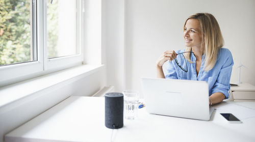 Smiling businesswoman looking away while sitting in office