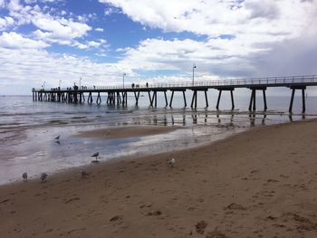 Pier on beach against sky