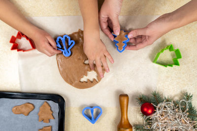 Mom and daughter with cookie cutters make christmas cookies from dough in the home kitchen. 