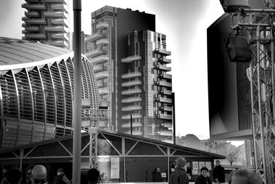 People on modern buildings in city against sky