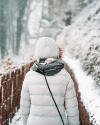 Rear view of woman walking on snow covered land