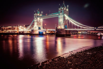 Illuminated bridge over river at night