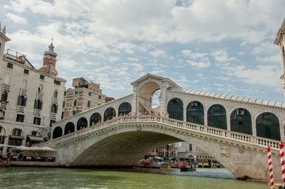 Arch bridge over canal against cloudy sky