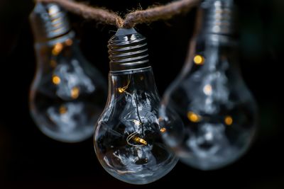 Close-up of light bulb hanging on rope outdoors