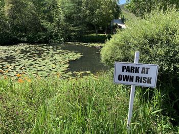 Information sign by lake against trees