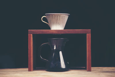 Close-up of black coffee in jar on table against black background