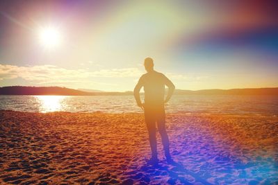 Silhouette woman standing at beach against sky during sunset