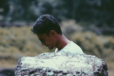 Side view of man standing by stone