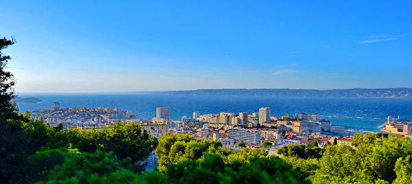 Scenic view of sea and cityscape against blue sky