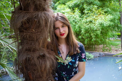 Portrait of young woman wearing hat against trees