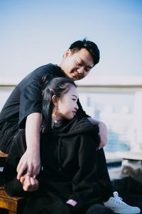 Young couple kissing against sky