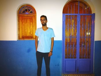 Full length portrait of young man standing against building