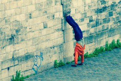 Full length of woman sitting on wall