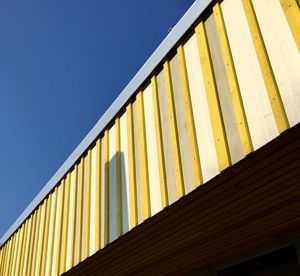 Low angle view of yellow built structure against clear blue sky