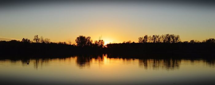 Scenic view of lake against clear sky during sunset