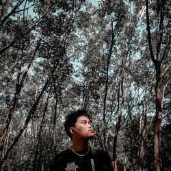 Portrait of young man looking away in forest