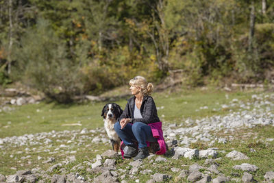 Rear view of woman with dog sitting outdoors