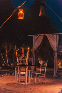 Illuminated lighting equipment on table against trees at night