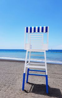 Deck chairs on beach against clear blue sky