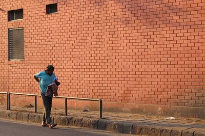 Full length of woman standing against brick wall