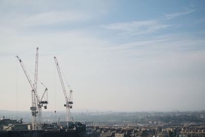 Cranes in city against sky