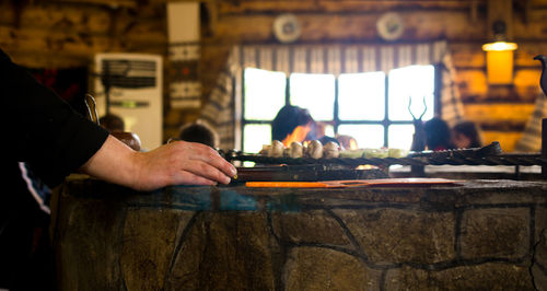 Cropped hand of chef grilling mushrooms on barbecue