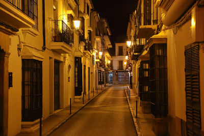 Narrow street amidst buildings at night