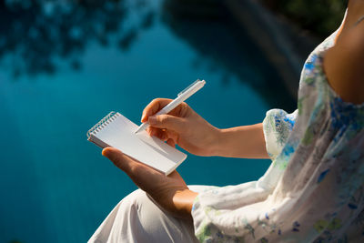 Close-up of woman holding mobile phone against sky