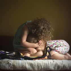 Siblings sitting on bed at home