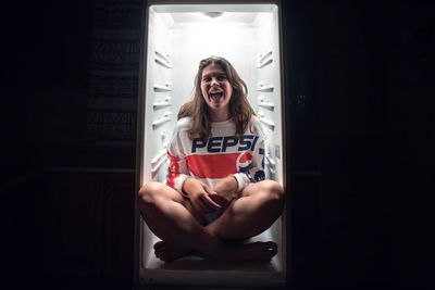 Portrait of a smiling young woman sitting on door