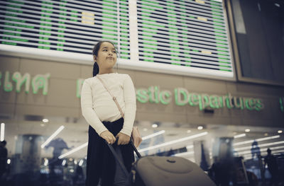 Low angle view of girl looking away while standing at airport