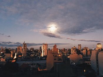 Illuminated cityscape against cloudy sky