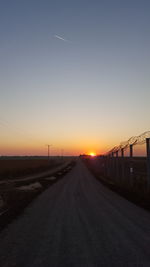 Empty road along countryside landscape at sunset