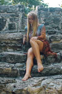 Full length of woman sitting on rock