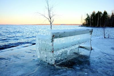 Frozen sea against clear sky during sunset