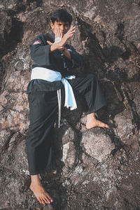 Side view of young man standing on rock