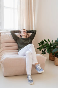 Minimal light and airy interior design. attractive young woman in white jeans and green sweater sitt