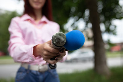 Midsection of woman holding microphone