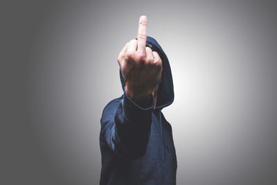 Midsection of person wearing hat standing against gray background