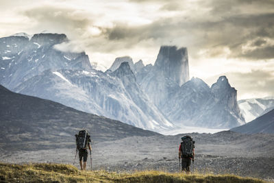 Rear view of people on snowcapped mountain against sky