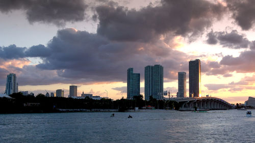 Scenic view of sea by buildings against sky during sunset