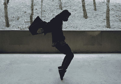 Side view of man jumping against wall