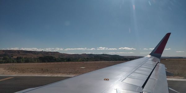 Airplane flying over landscape against blue sky