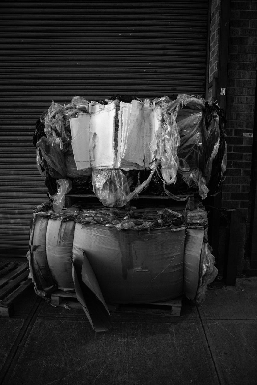 STACK OF GARBAGE ON SOFA AGAINST ABANDONED HOUSE